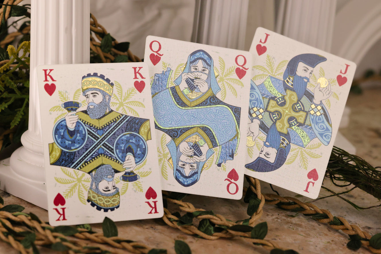 Three court cards featuring kings, queens, and jacks with decorative designs on a decorative stand.