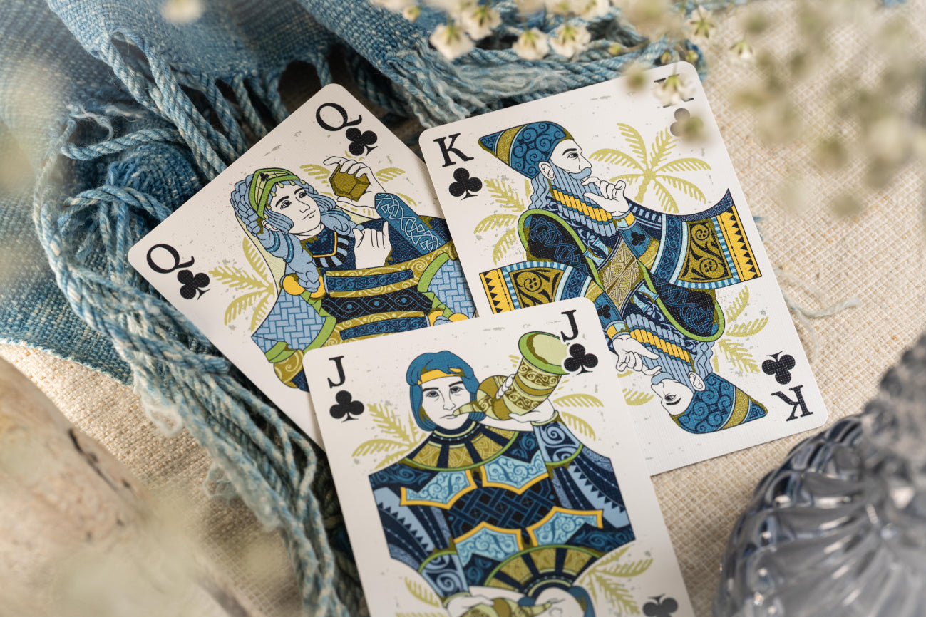 Three Court cards featuring queens, kings, and jacks on a textured surface with floral elements.