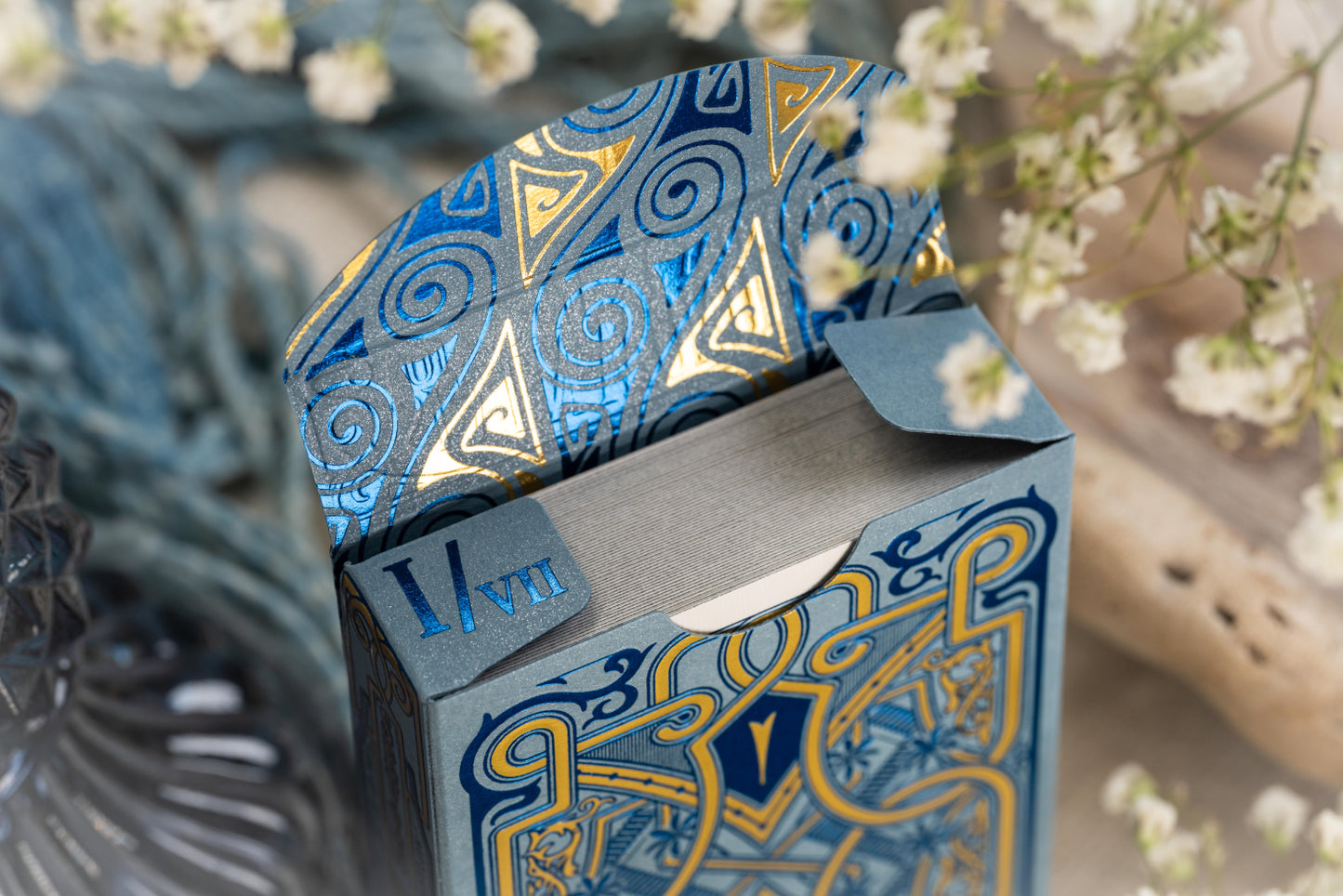 Opened Standard Edition tuck box with blue and gold patterns on a blurred natural background