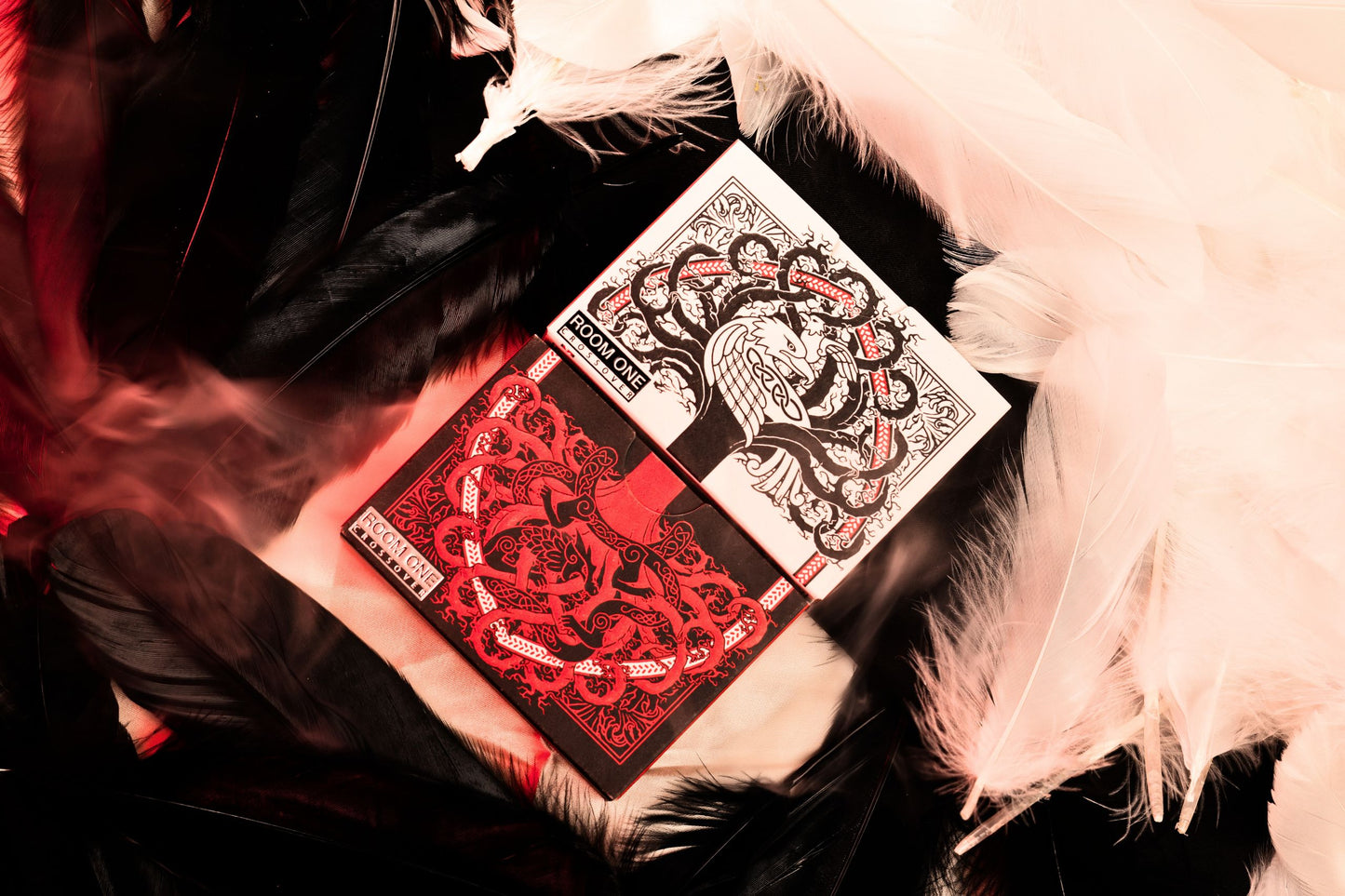 Both mythic edition Mythic Divide playing cards with intricate designs on a dark surface with feathers.