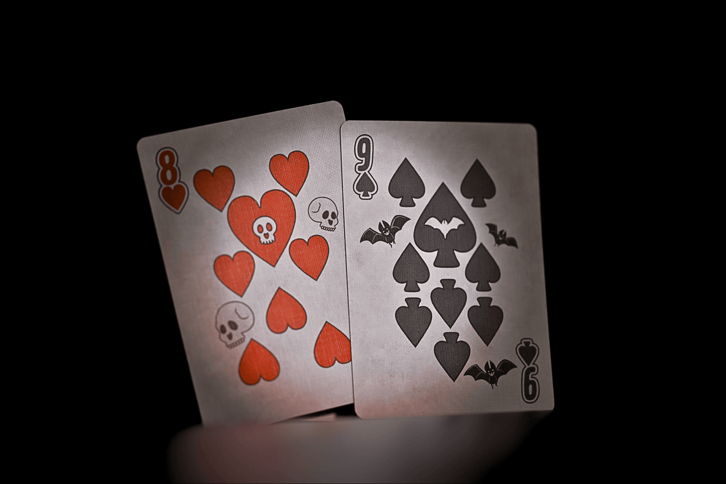 Two playing cards with red hearts and black spades on a dark background