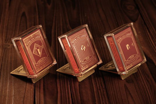 Three decks of cards with gold and red design on a brown textured background