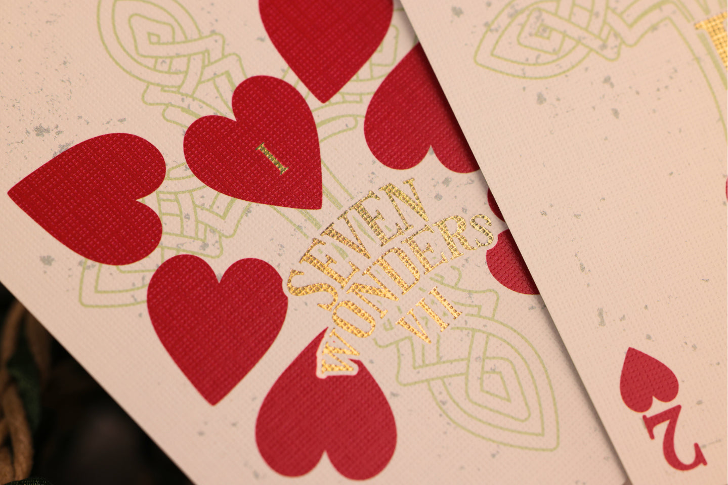 Close-up of playing cards with red hearts and gold foil detailing.