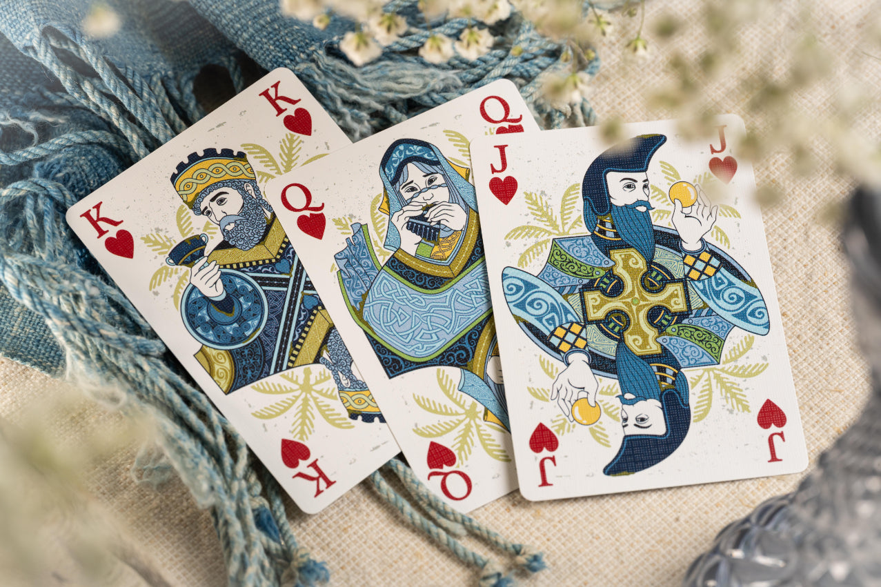 Three playing cards with decorative designs on a textured surface.