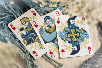 Three playing cards with decorative designs on a textured surface.