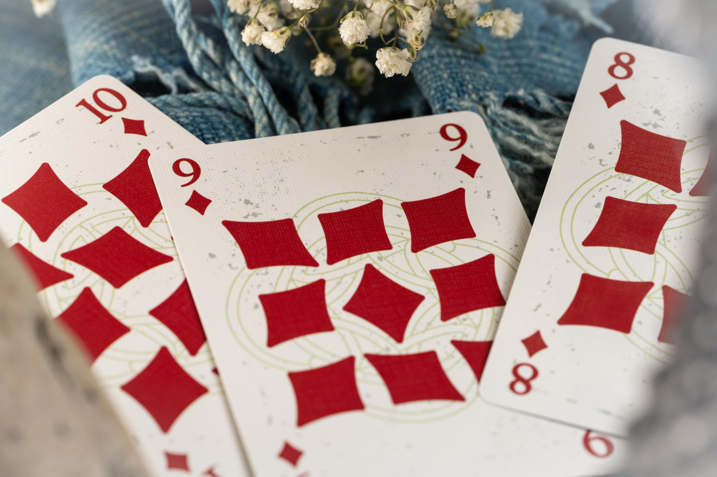 Three playing cards with red diamond suits on a blurred background