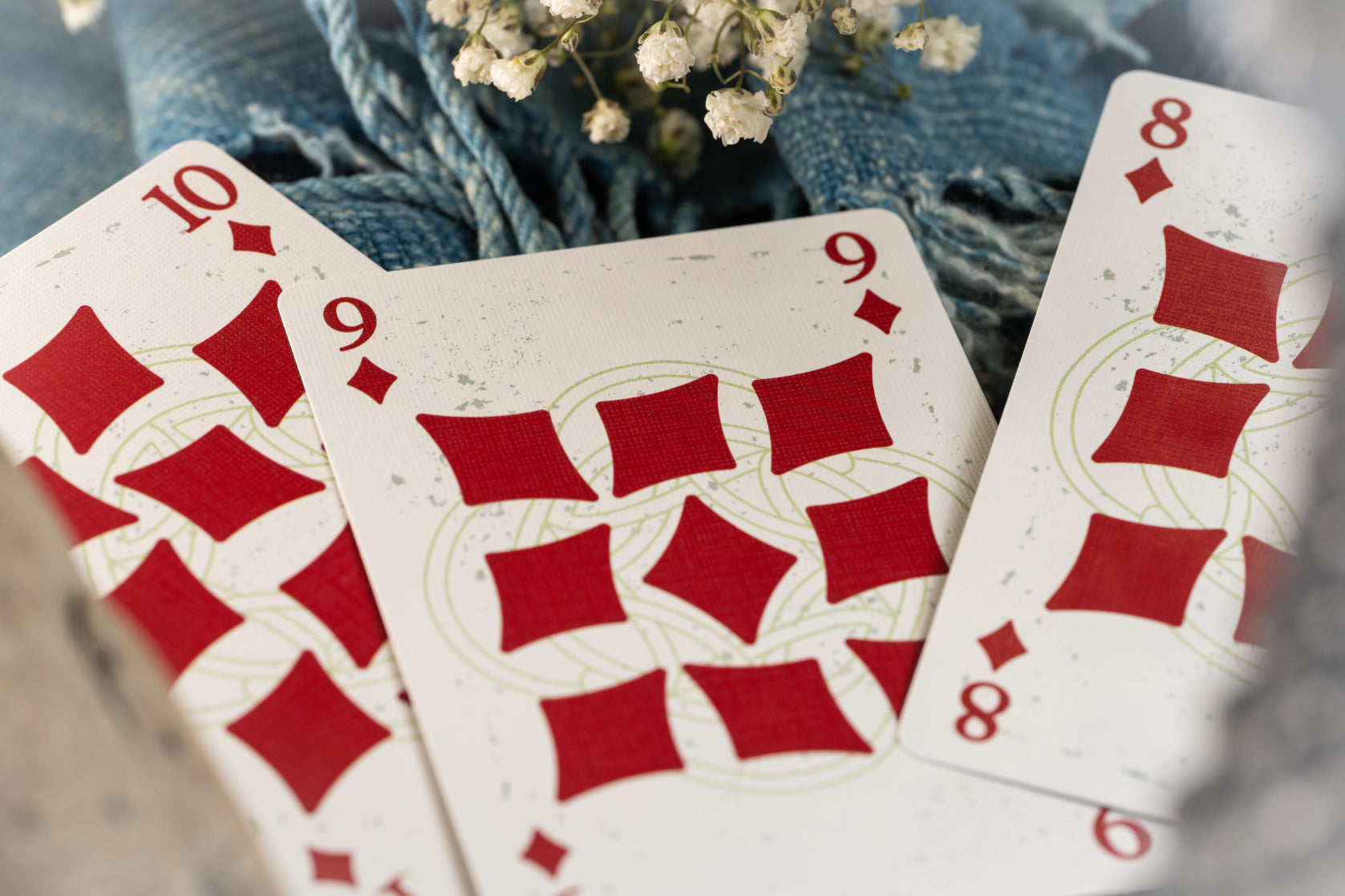 Three playing cards with red diamond suits on a blurred background