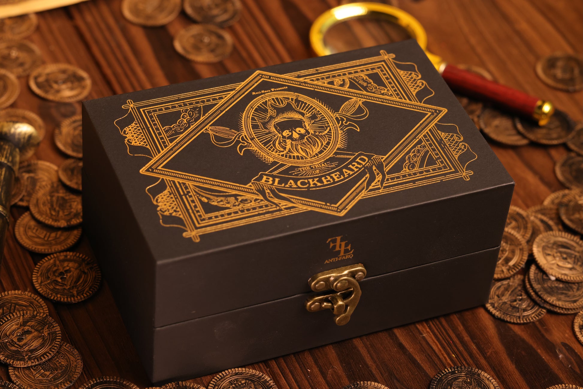Black collector's box with gold detailing on a wooden surface with coins and a magnifying glass.