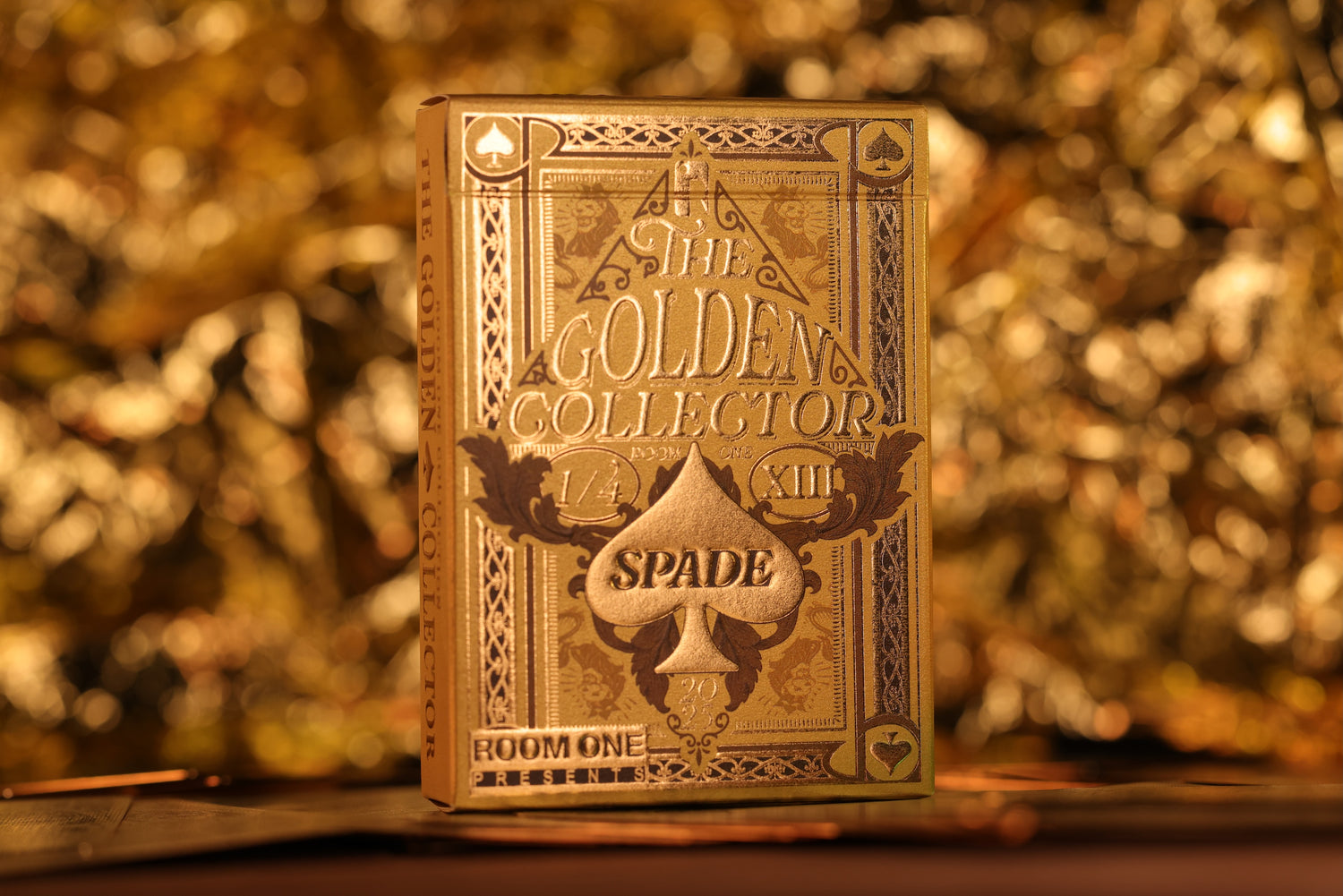 Gold playing card box with 'The Golden Collector' branding on a blurred gold background
