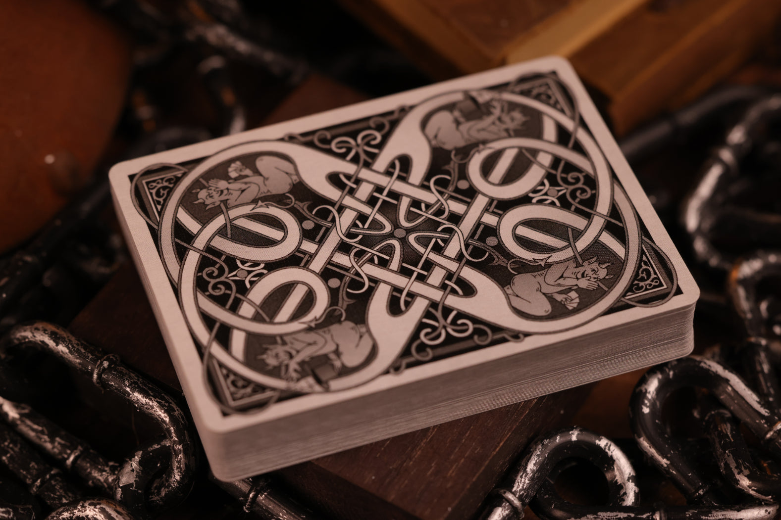 Clubs edition card backs with an intricate design on a wooden surface with chains