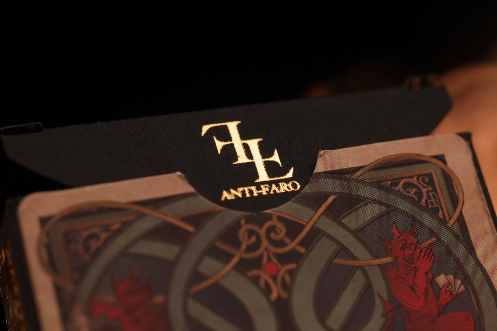 Close-up of playing cards with intricate designs and a golden hot-foil 'Anti-Faro' branding.