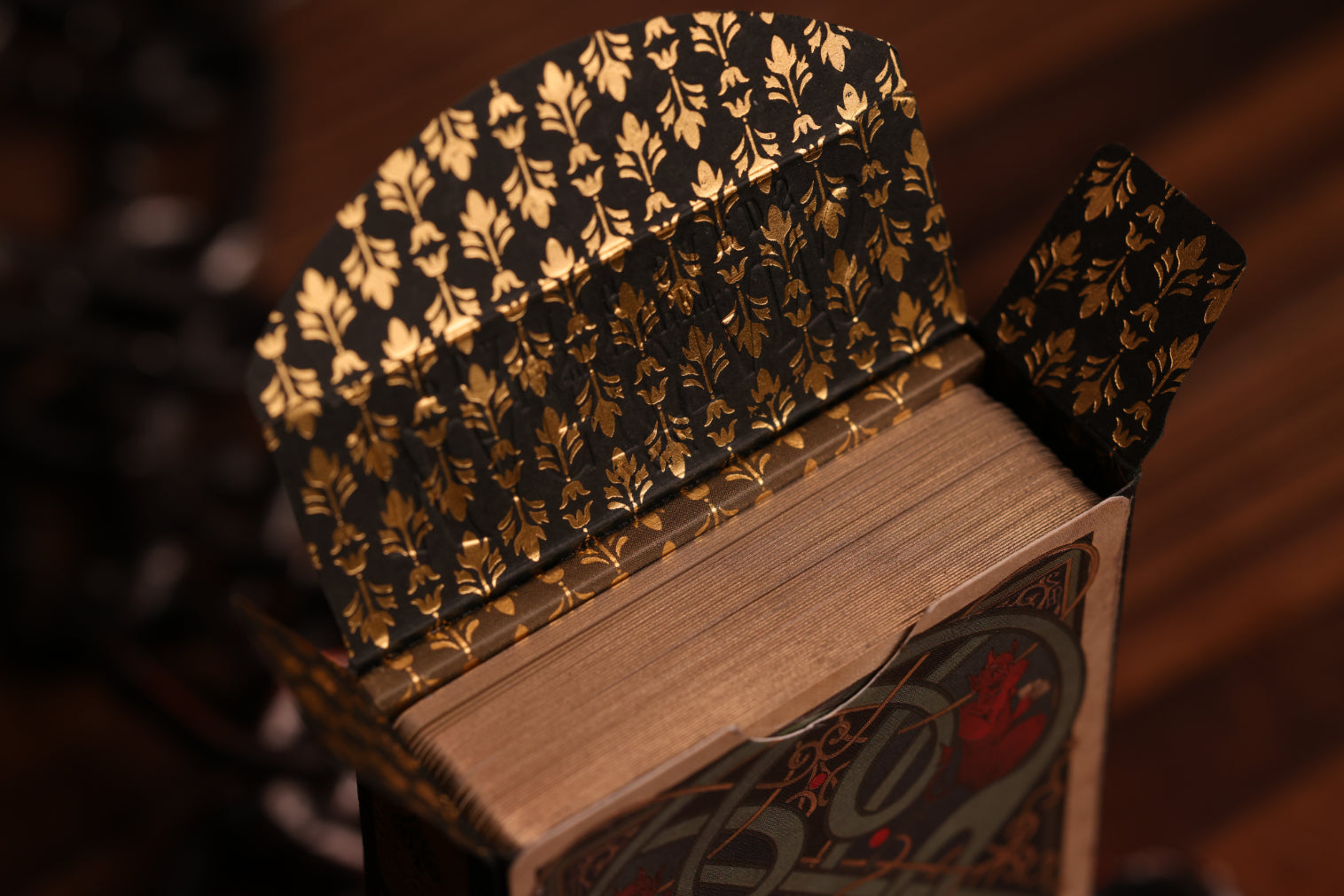 Close-up of the Spades Edition Tuck box interior featuring an intricate metallic gold hot foil pattern on a dark background