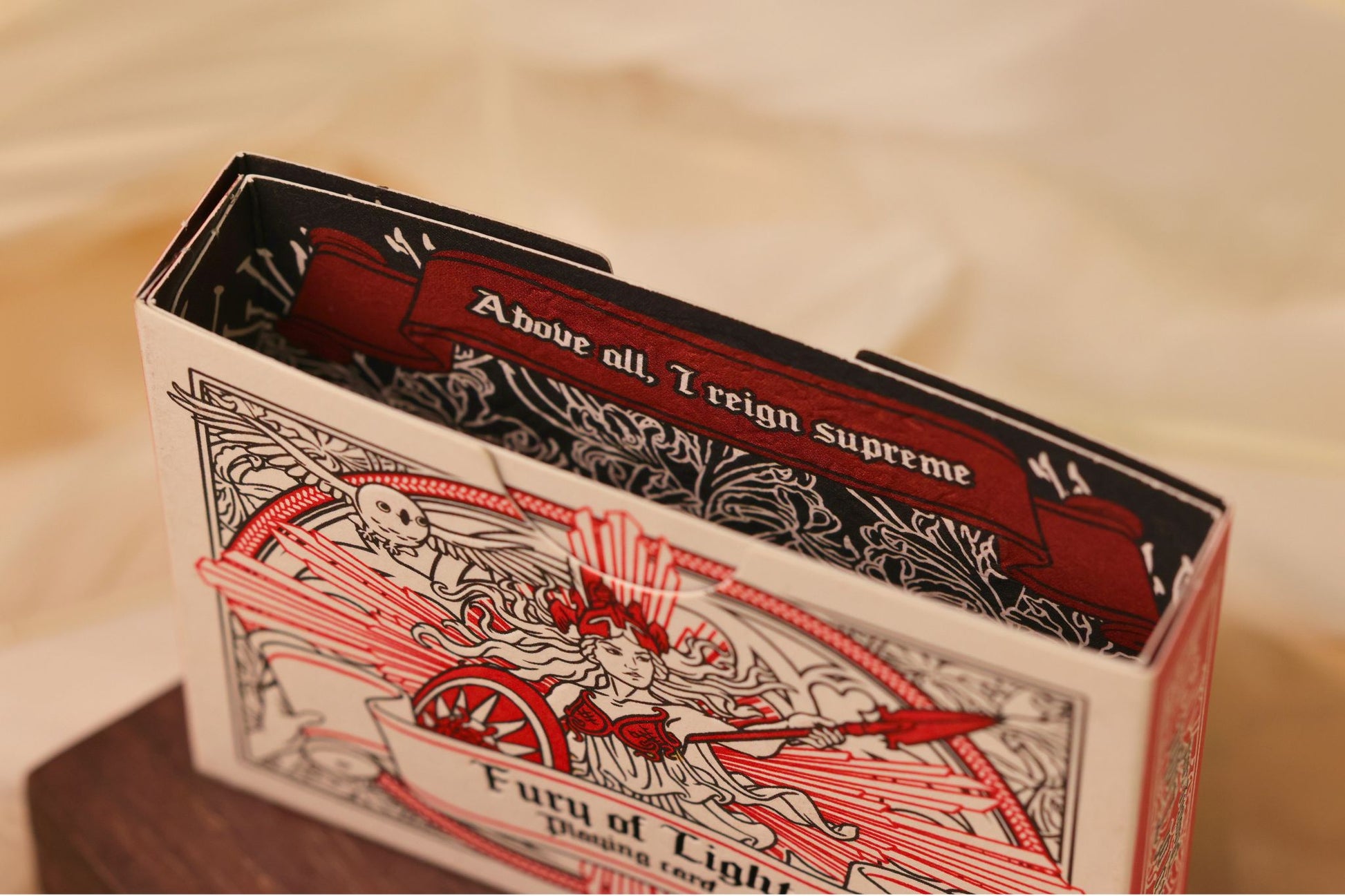 MYTHIC edition Fury of Light tuck box interior with intricate illustrated design on a bed of feathers.