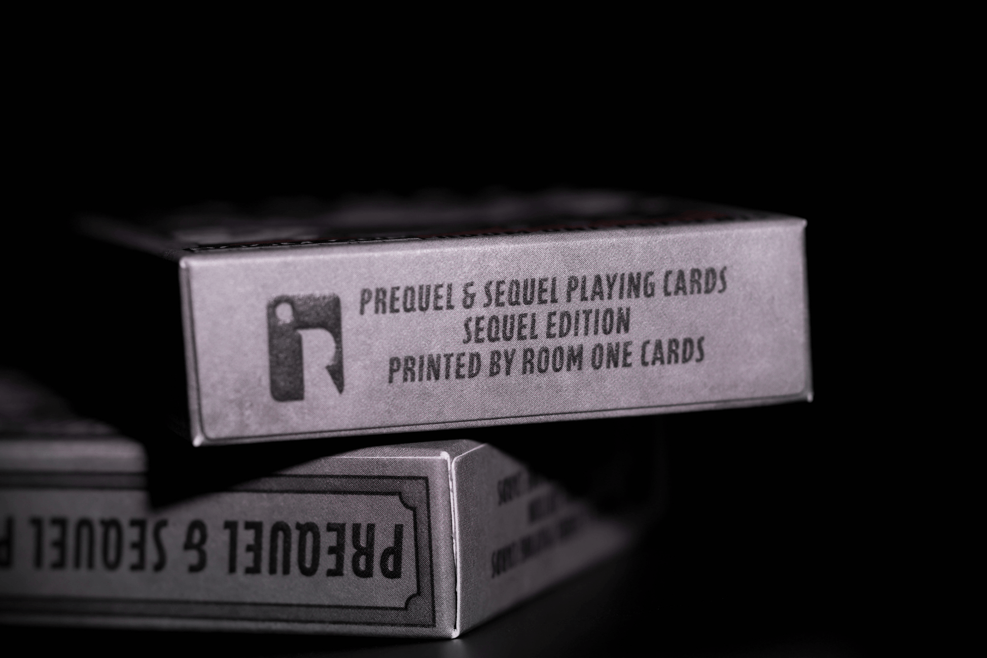 Stack of 'Prequel & Sequel Playing Cards' boxes with text on a dark background