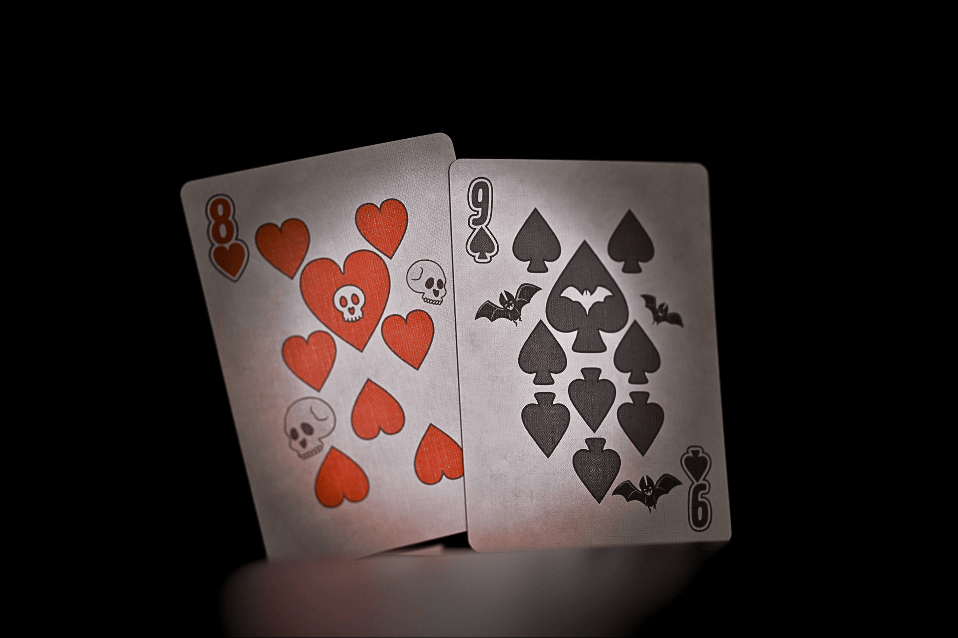 Two playing cards with red hearts and black spades on a dark background